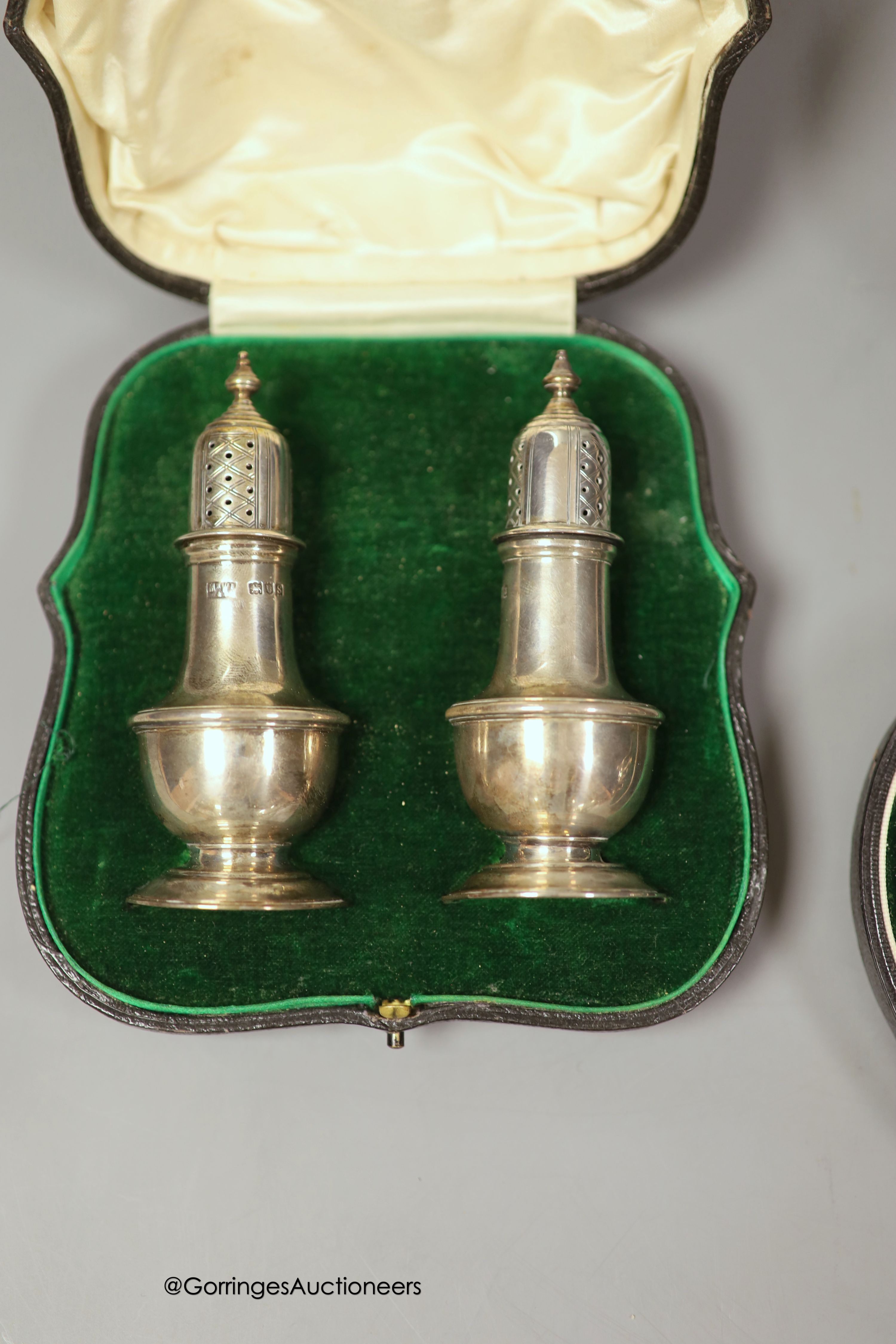 A cased pair of George V silver pepperettes, Mappin & Webb, London, 1913, 11.3cm and a cased harlequin four piece silver condiment set.